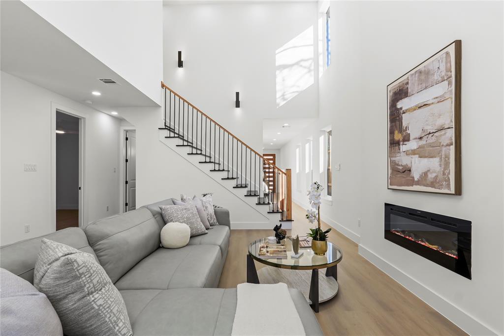 459 Hart Street Dallas, TX 75203 - Photo 7 of 21 Living room with a high ceiling, a glass covered fireplace, stairs, wood finished floors, and recessed lighting