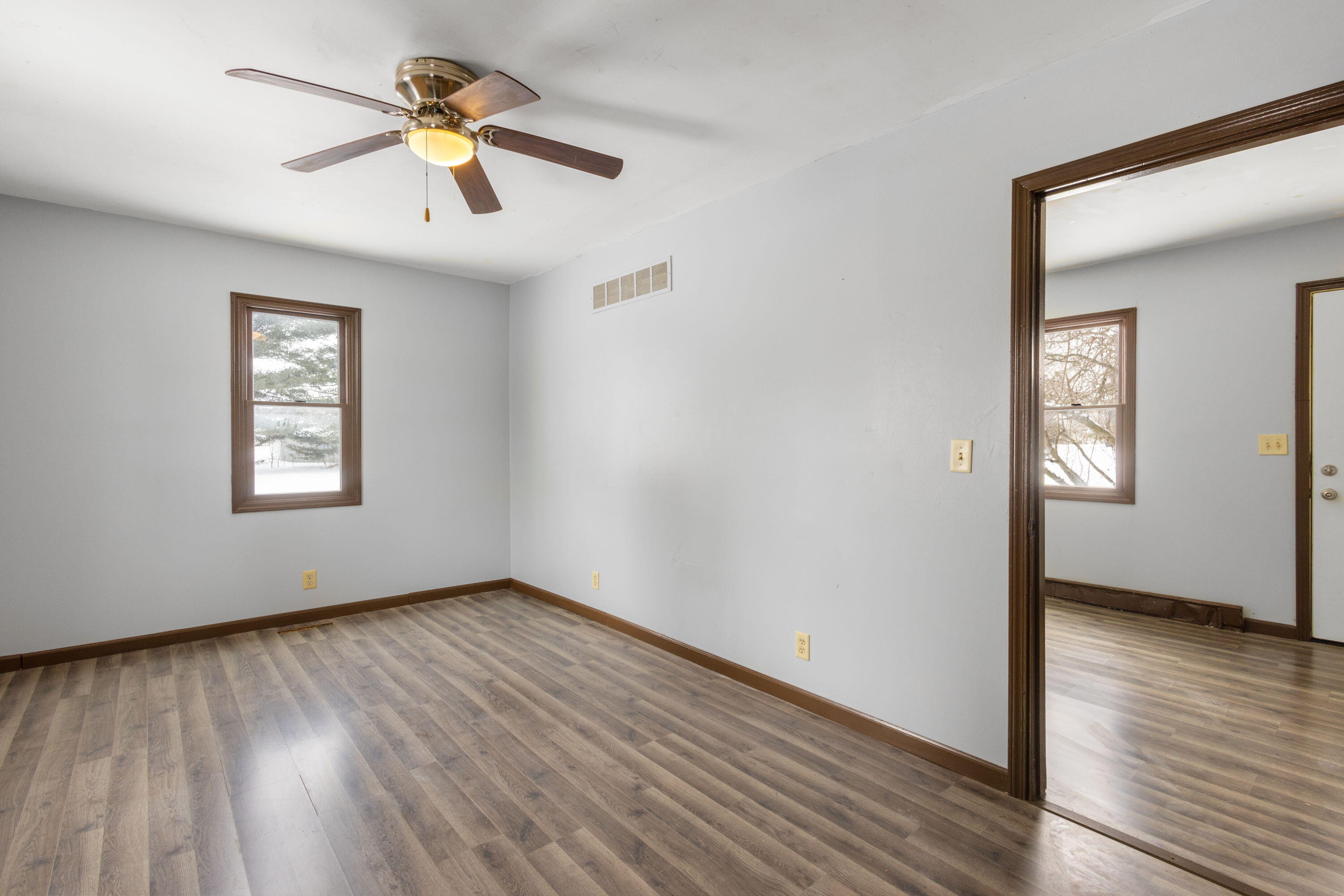 203 North Main Street Kingsbury, IN 46350 - Photo 13 of 32 an empty room with wooden floor chandelier fan and windows