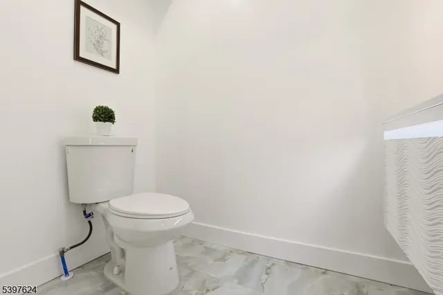a white toilet sitting next to a white wall