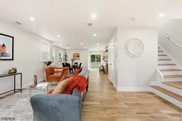 a living room with furniture kitchen view and a wooden floor