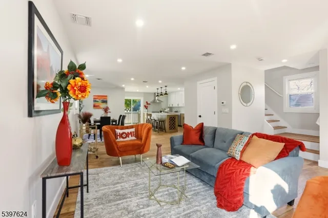 a living room with furniture kitchen view and a chandelier