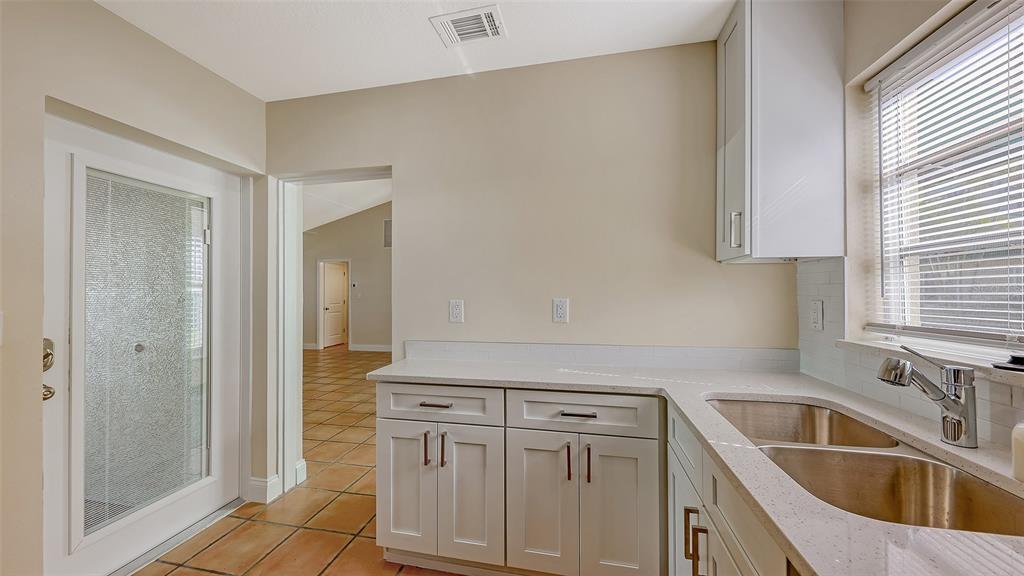 5860 Midnight Pass Road, Unit 40 Sarasota, FL 34242 - Photo 6 of 37 a kitchen with white cabinets a sink and a stove with wooden floor