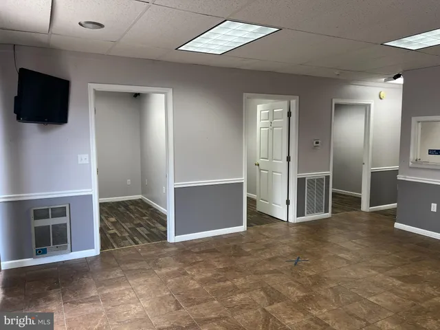 a view of an empty room with kitchen and a window