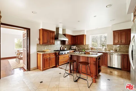 a kitchen with stainless steel appliances granite countertop a stove top oven a sink dishwasher a dining table and chairs with wooden floor