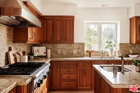 a kitchen with granite countertop a sink a stove and wooden cabinets