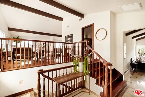 a view of staircase with lots of frames on wall and wooden floor