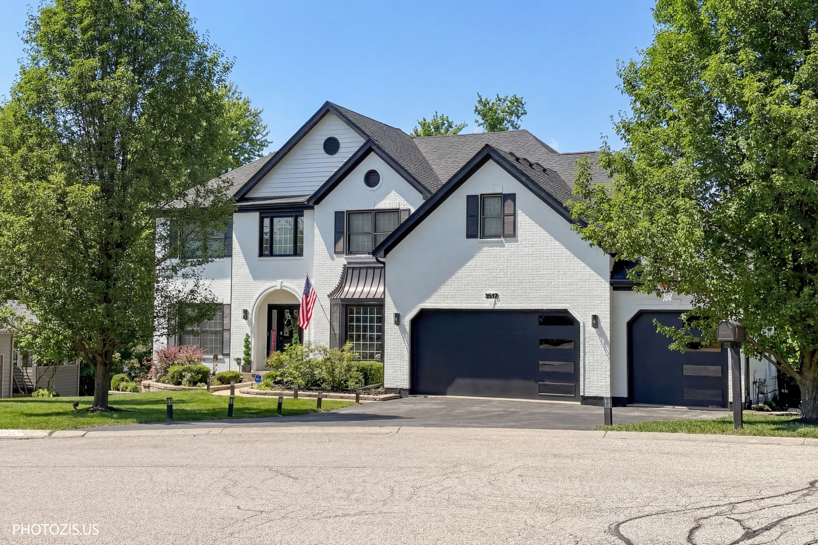 a front view of a house with a garden and trees