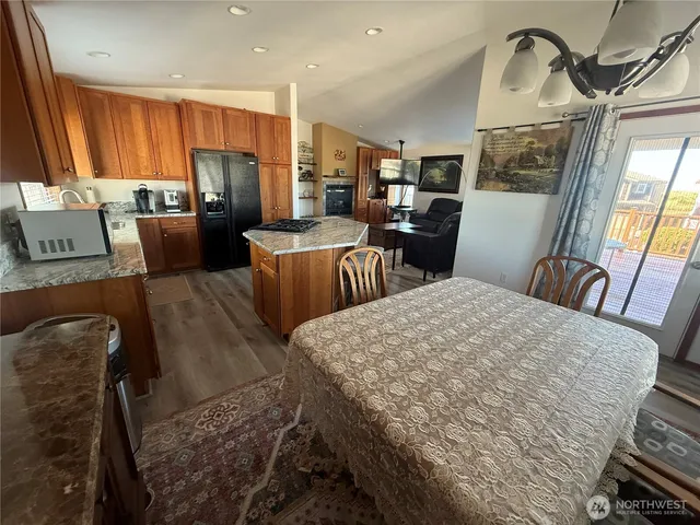 a kitchen with stainless steel appliances kitchen island granite countertop a refrigerator a stove a microwave oven with a dining table and chairs