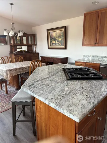 a kitchen view with granite countertop a table chairs sink and cabinets