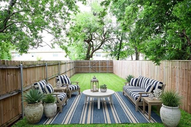 802 South 5th Street, Unit 1 Bonham, TX 75418 - Photo 12 of 25 Expansive fenced backyard featuring a manicured lawn, mature trees, and a wooden privacy fence