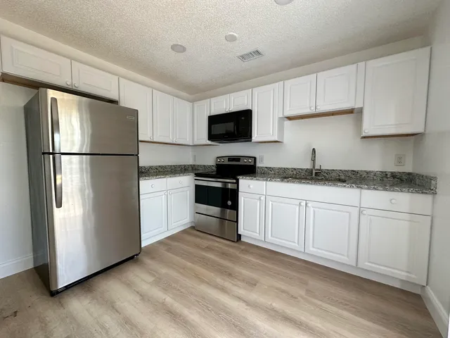 a kitchen with a refrigerator sink and white cabinets