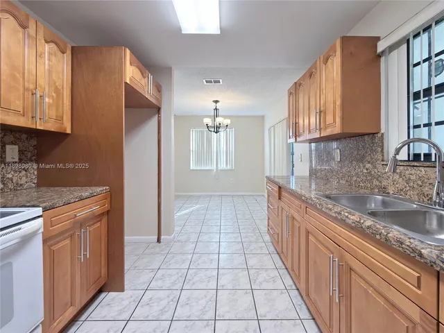 a large kitchen with stainless steel appliances granite countertop a sink and cabinets