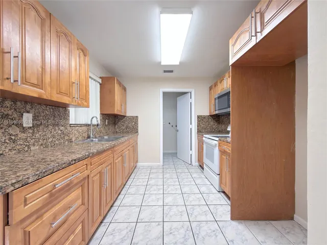 a large kitchen with granite countertop a stove a sink dishwasher and a refrigerator