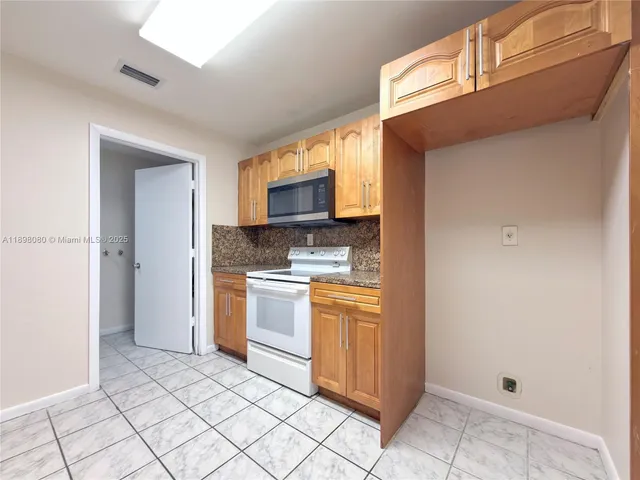 a kitchen with granite countertop a refrigerator and a stove top oven