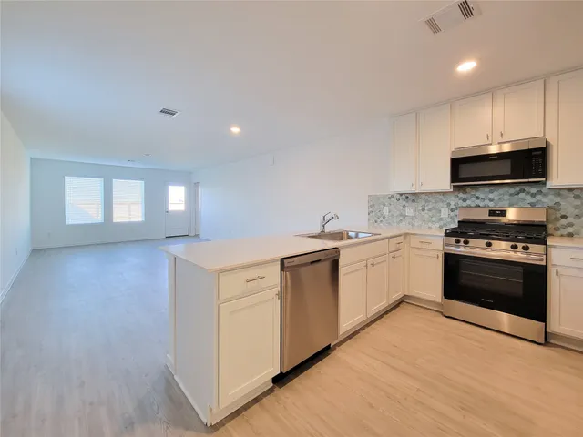 a kitchen with granite countertop a stove top oven and cabinets