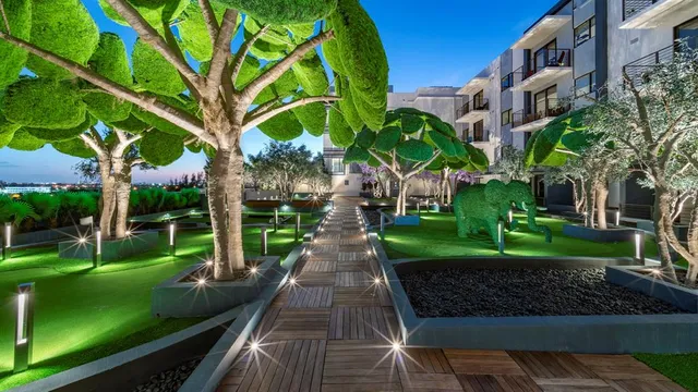 a view of a yard with plants and large trees