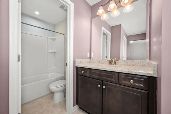 a bathroom with a granite countertop sink a toilet a mirror and shower