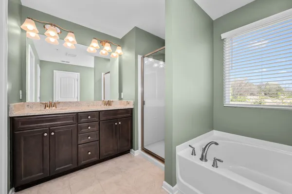 a bathroom with a tub sink double vanity and a mirror