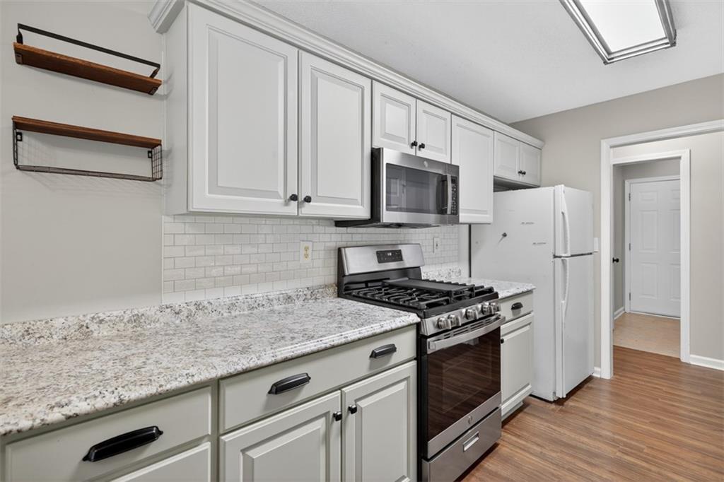 5683 Riverside Walk Drive Northeast Sugar Hill, GA 30518 - Photo 17 of 42 a kitchen with granite countertop a sink stove and refrigerator