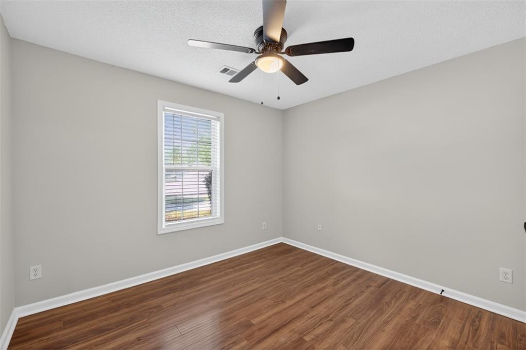 5683 Riverside Walk Drive Northeast Sugar Hill, GA 30518 - Photo 19 of 42 an empty room with wooden floor ceiling fan and windows