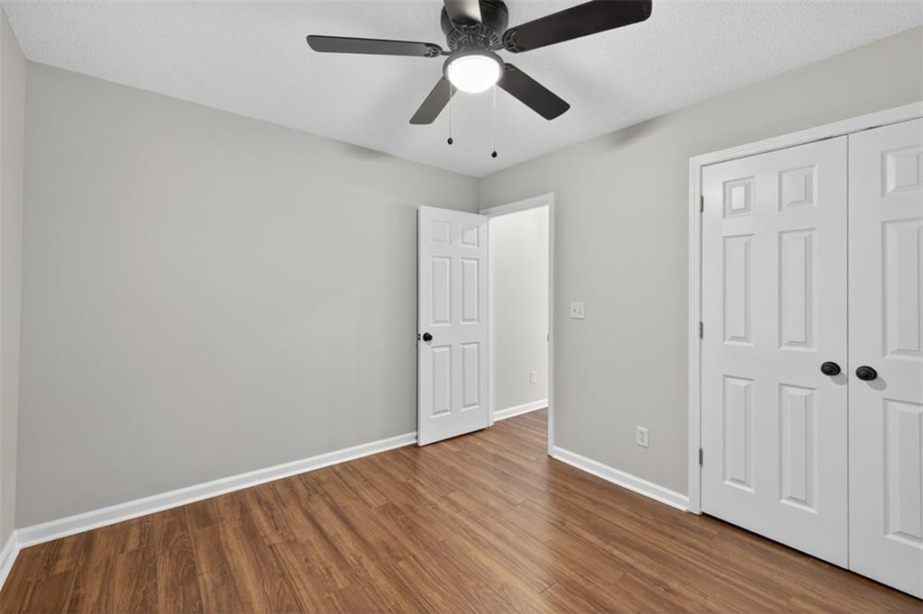 5683 Riverside Walk Drive Northeast Sugar Hill, GA 30518 - Photo 22 of 42 an empty room with wooden floor ceiling fan and windows