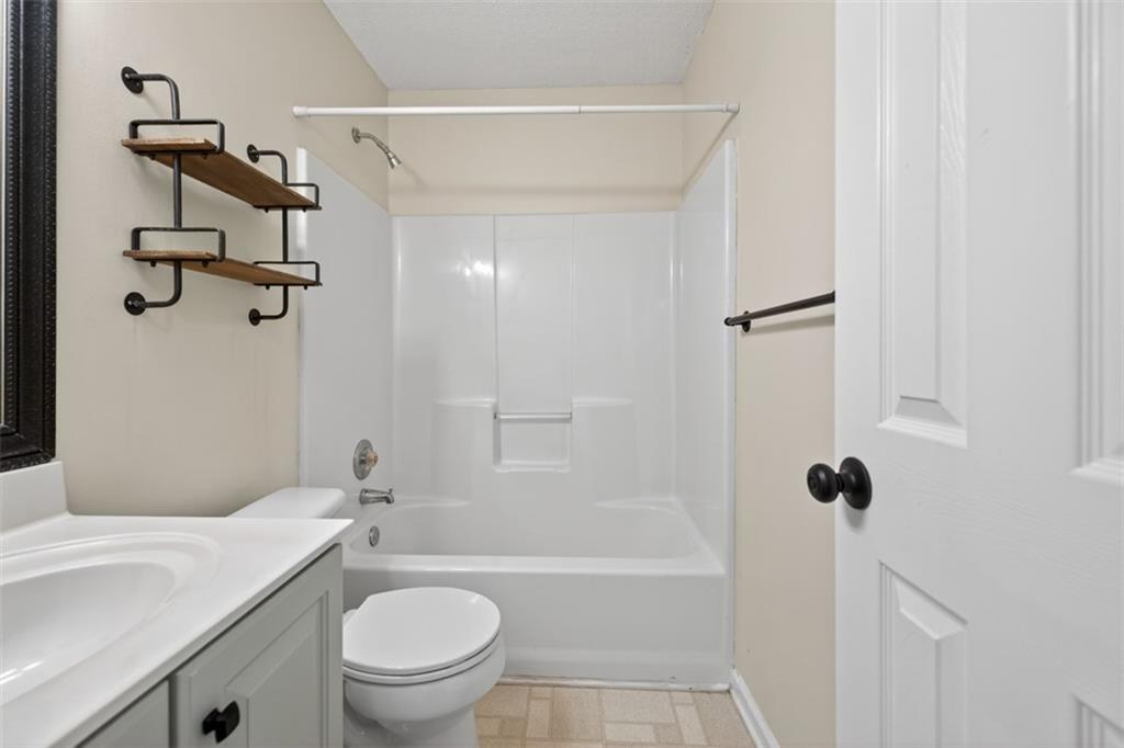 5683 Riverside Walk Drive Northeast Sugar Hill, GA 30518 - Photo 24 of 42 a bathroom with a granite countertop toilet a sink and a bathtub