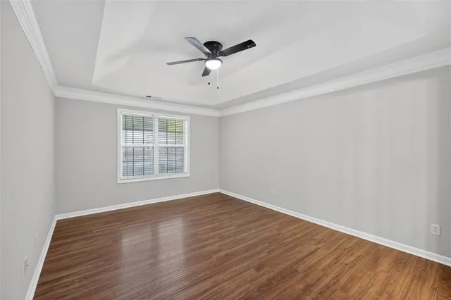an empty room with wooden floor ceiling fan and window