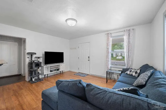 a view of an empty room with a window and wooden floor