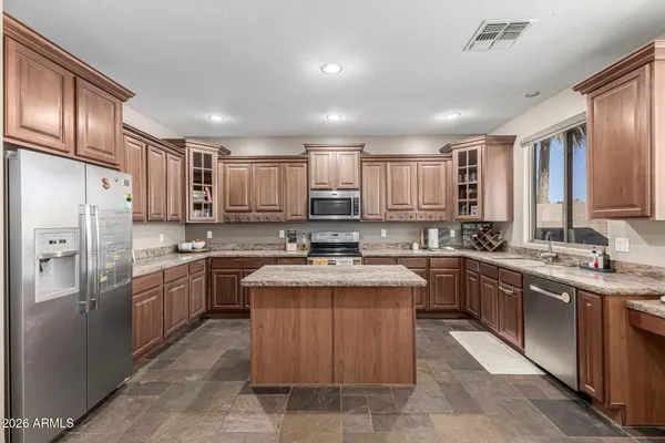 a kitchen with stainless steel appliances granite countertop a sink stove refrigerator and cabinets