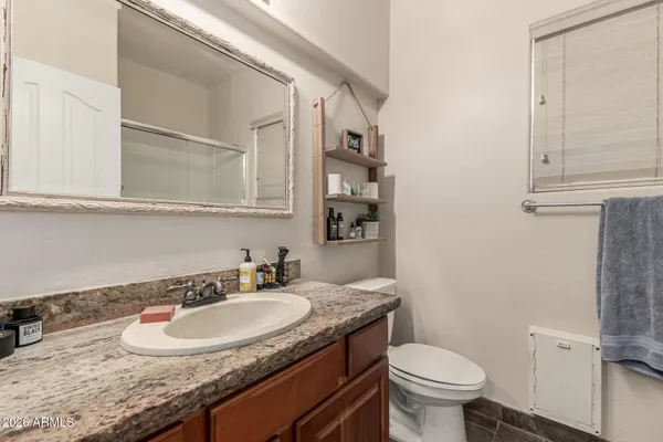 a bathroom with a granite countertop sink a toilet and a mirror
