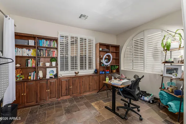 a work room with furniture a bookshelf and a window