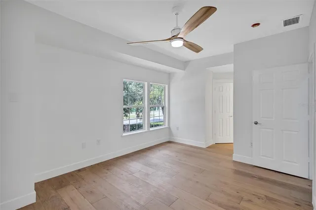 a view of a room with wooden floor and ceiling fan