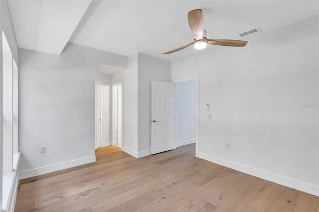 an empty room with wooden floor and ceiling fan