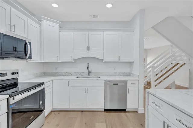 a kitchen with white cabinets stainless steel appliances and sink
