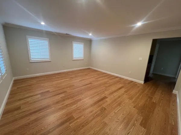 an empty room with wooden floor and windows