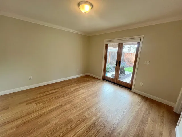 a view of an empty room with wooden floor and window