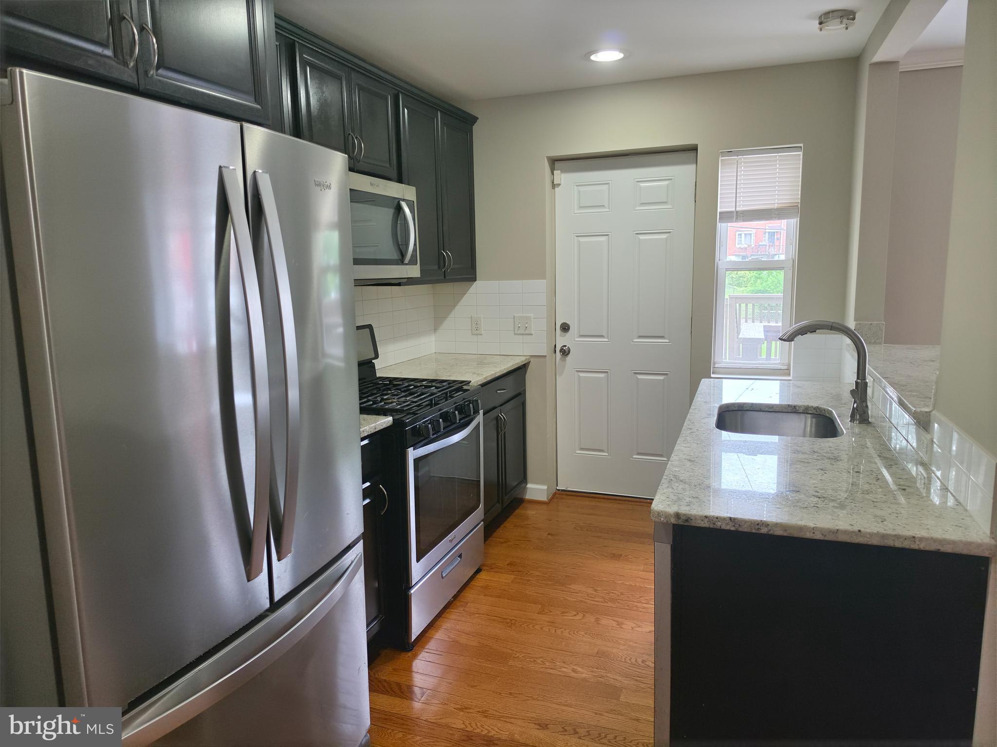 2028 Hillenwood Road Baltimore, MD 21239 - Photo 4 of 18 a kitchen with stainless steel appliances granite countertop a refrigerator a stove and a sink with wooden floor