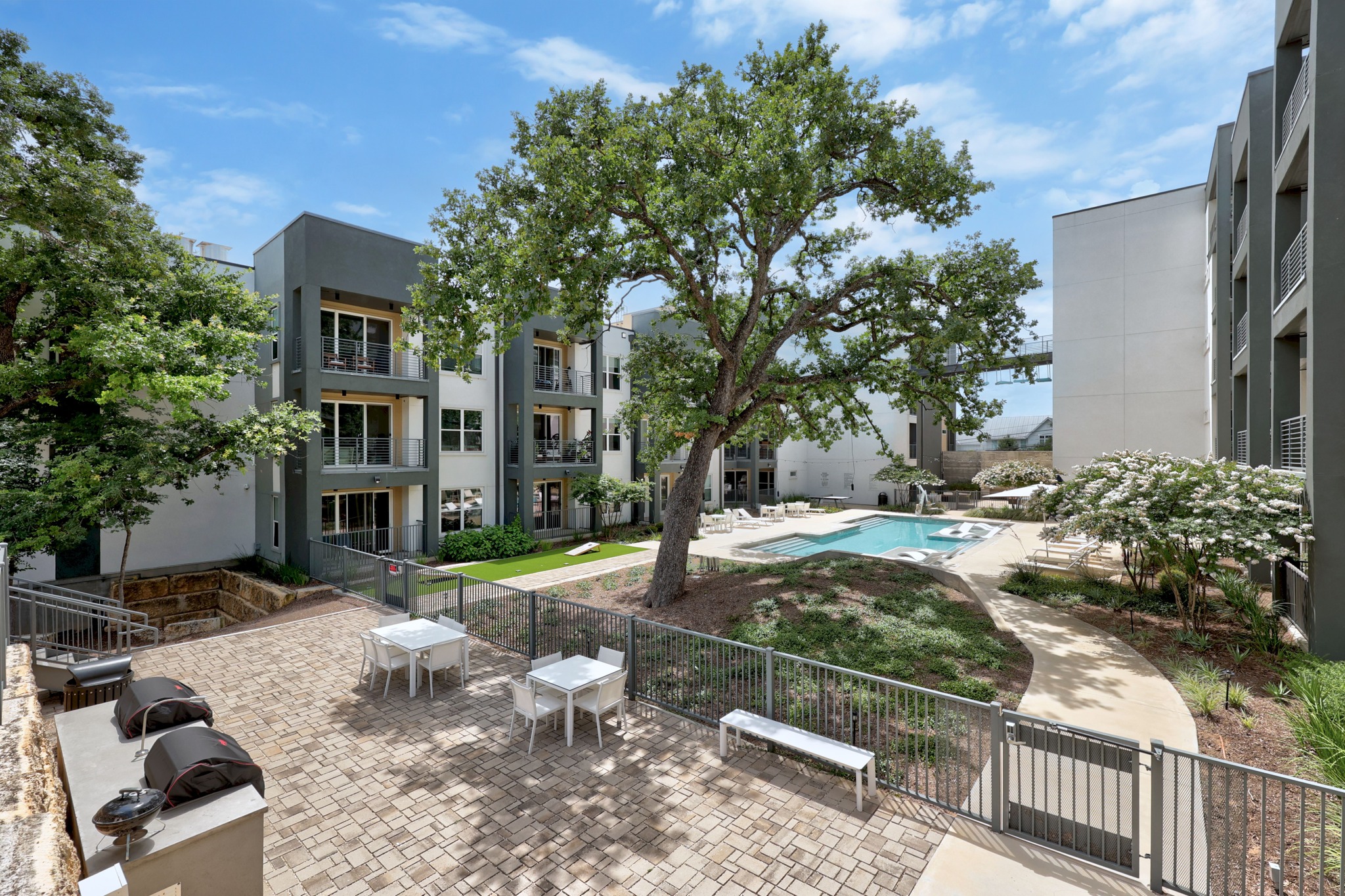 4801 Springdale Road, Unit 2301 Austin, TX 78723 - Photo 26 of 36 Lush landscaping surrounds a sparkling pool and outdoor dining areas for relaxed living.