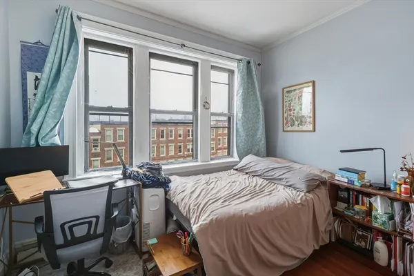 a bedroom with a bed a large window with table and chair