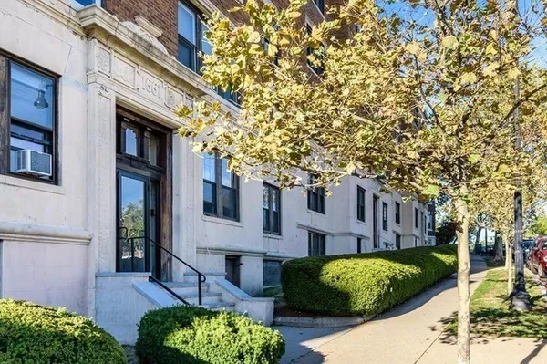 a view of a brick house with a yard and plants