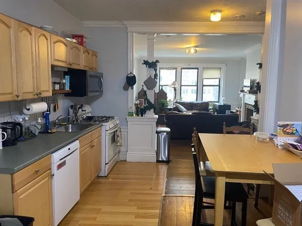 a kitchen with stainless steel appliances granite countertop a stove a sink dishwasher a microwave oven with a dining table and chairs with wooden floor