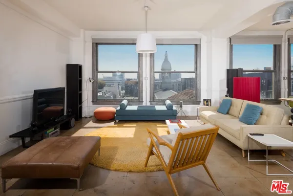 a living room with furniture a flat screen tv and a floor to ceiling window