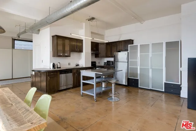 a living room with stainless steel appliances furniture a flat screen tv and kitchen view