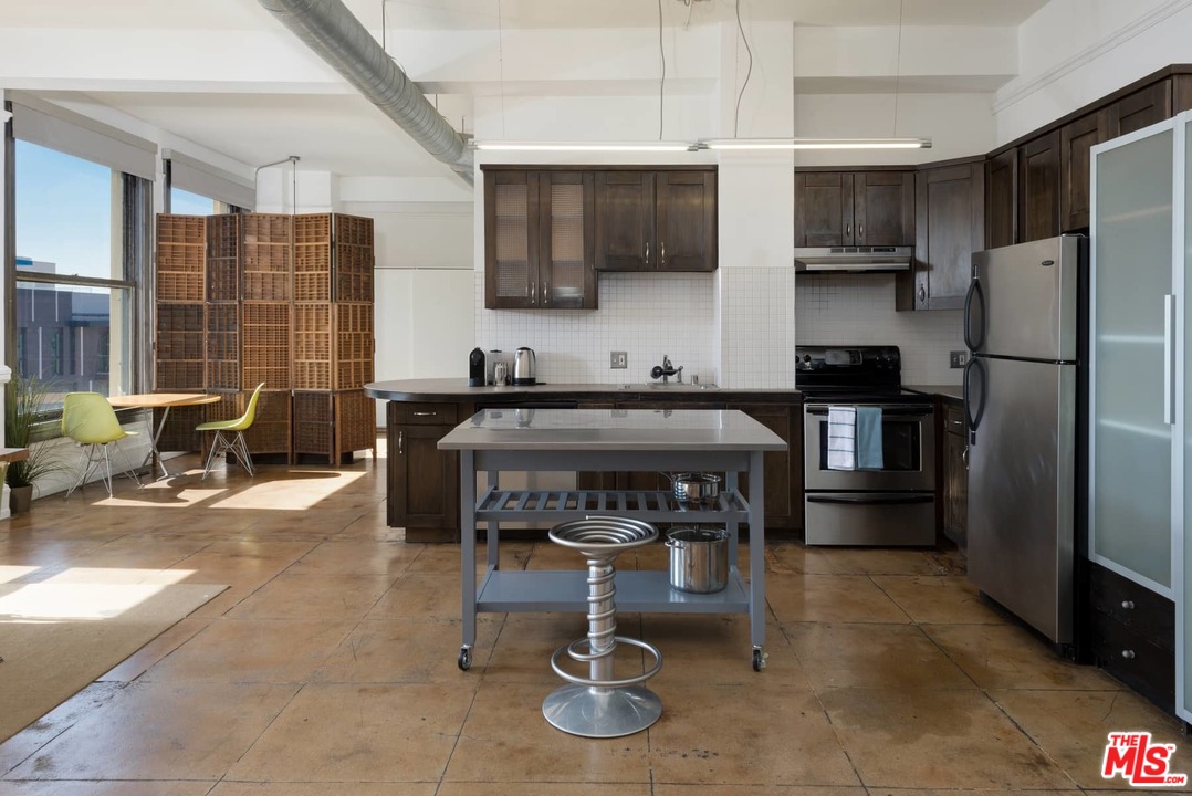 108 West 2nd Street, Unit 606 Los Angeles, CA 90012 - Photo 10 of 29 a kitchen with stainless steel appliances a refrigerator a stove a sink a dining table and chairs with wooden floor