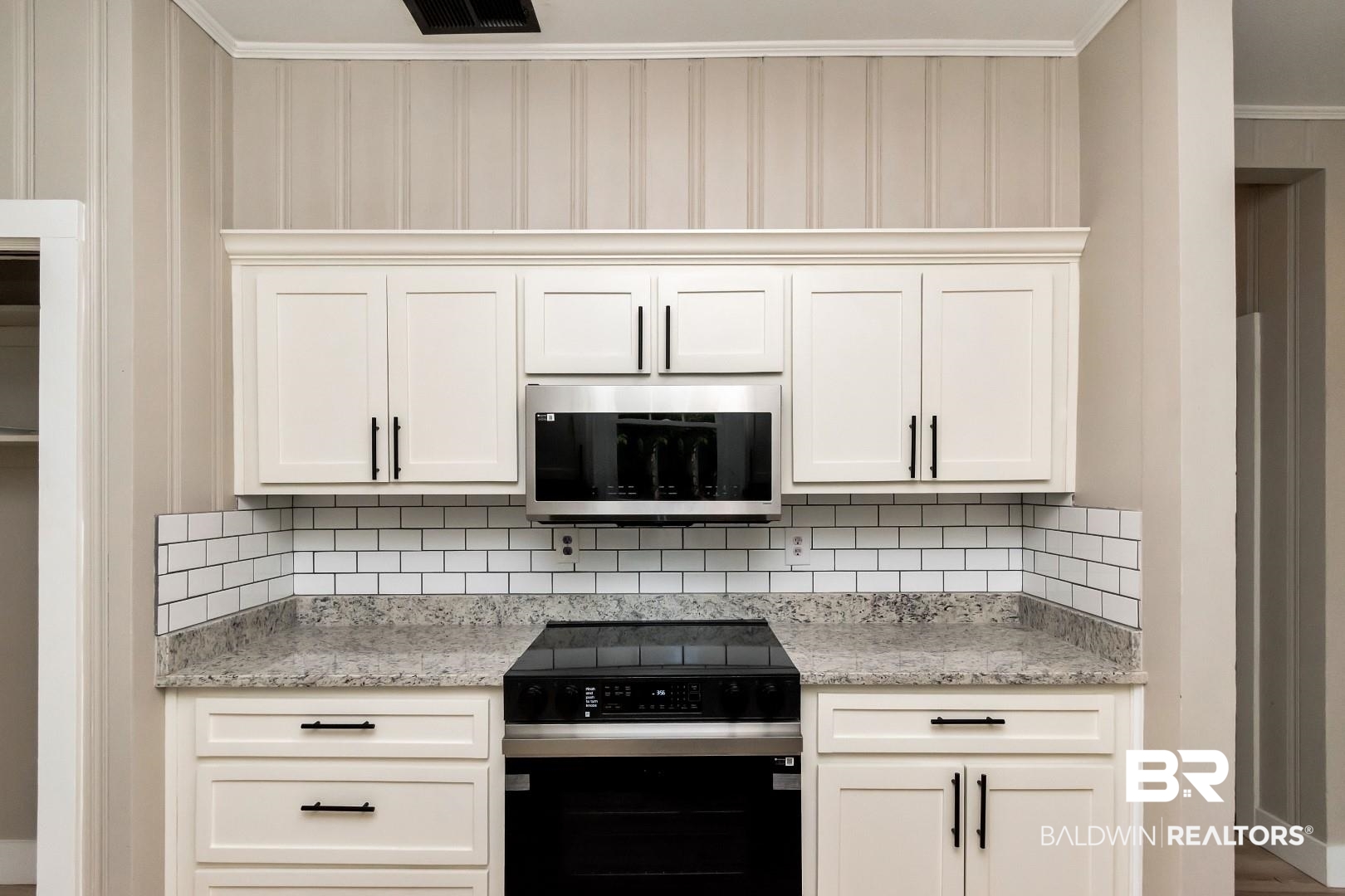 555 Michigan Avenue Mobile, AL 36604 - Photo 15 of 28 Kitchen featuring crown molding, backsplash, appliances with stainless steel finishes, light stone countertops, and white cabinets