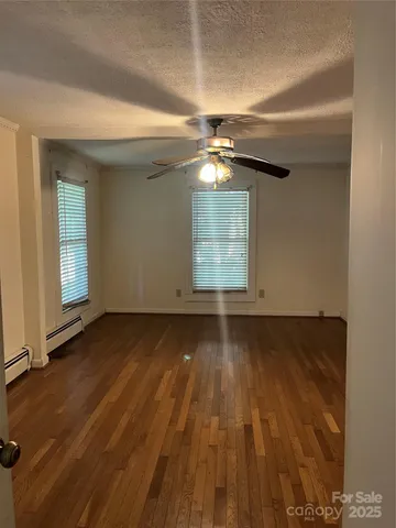 an empty room with wooden floor chandelier and windows
