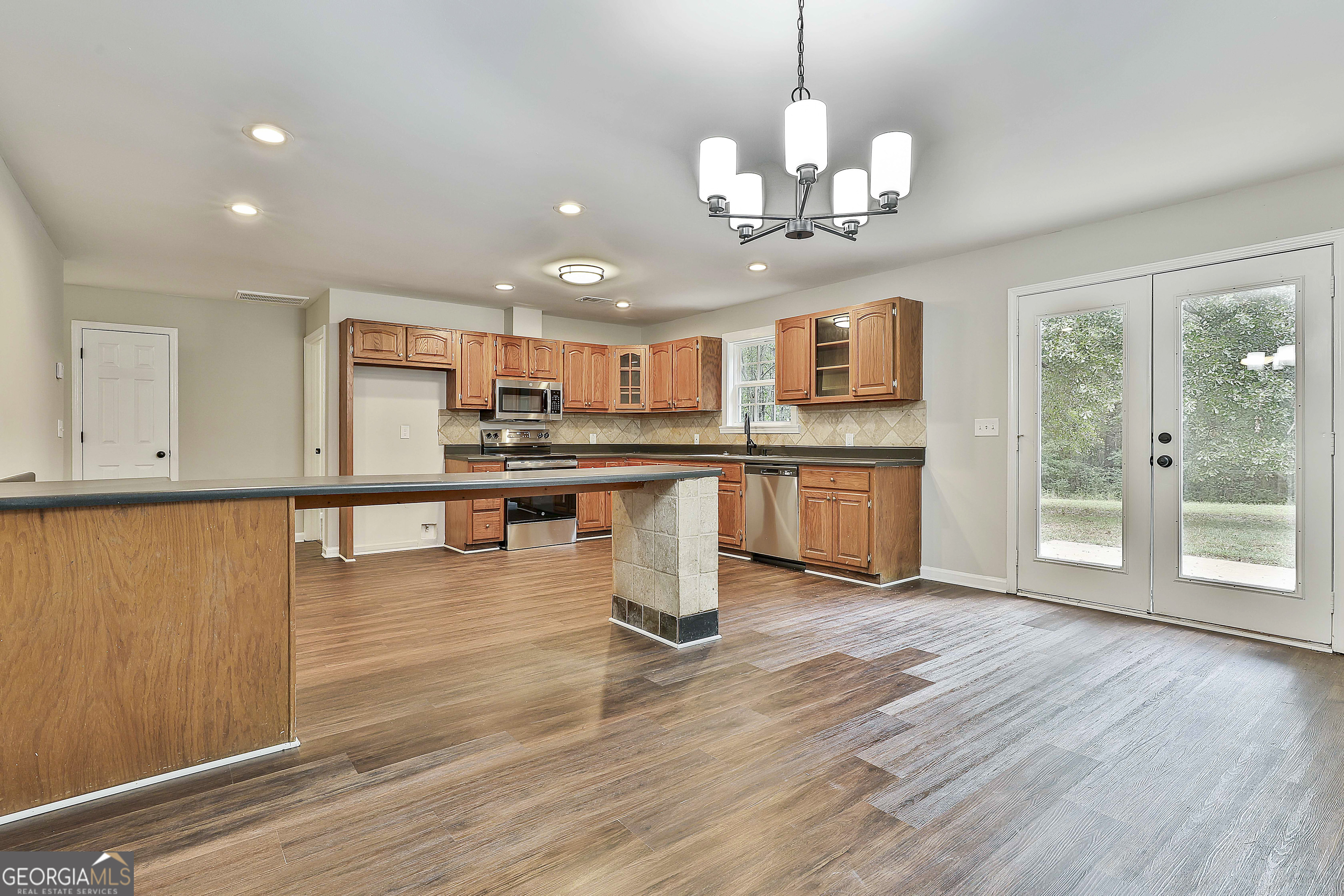 1606 Mcwilliams Barber Road Luthersville, GA 30251 - Photo 17 of 38 a kitchen with stainless steel appliances granite countertop a stove top oven a sink dishwasher and a dining table with wooden floor