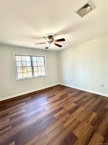 an empty room with wooden floor chandelier fan and windows