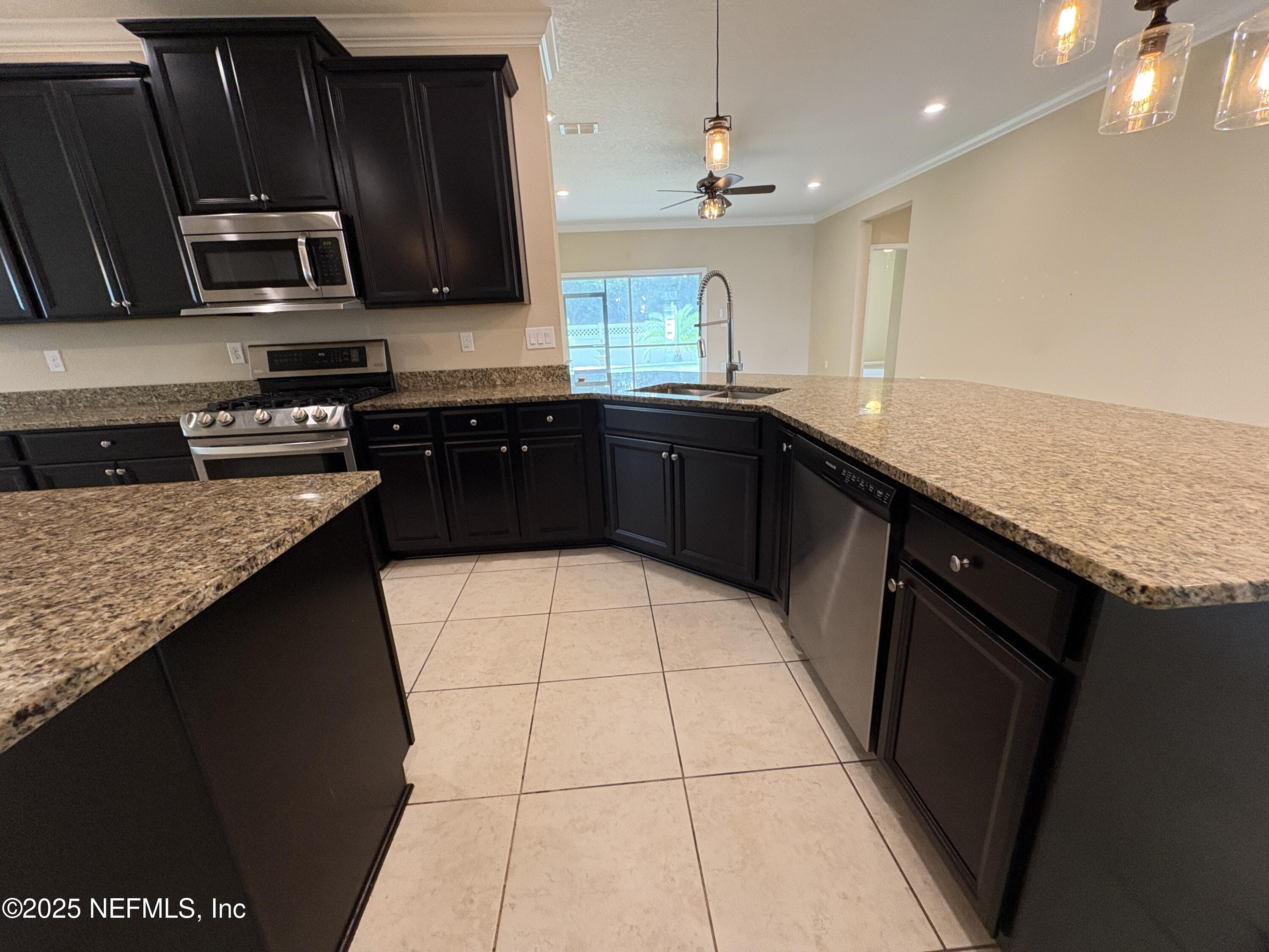 173 Athens Drive St. Augustine, FL 32092 - Photo 4 of 25 a kitchen with stainless steel appliances granite countertop a sink stove and microwave