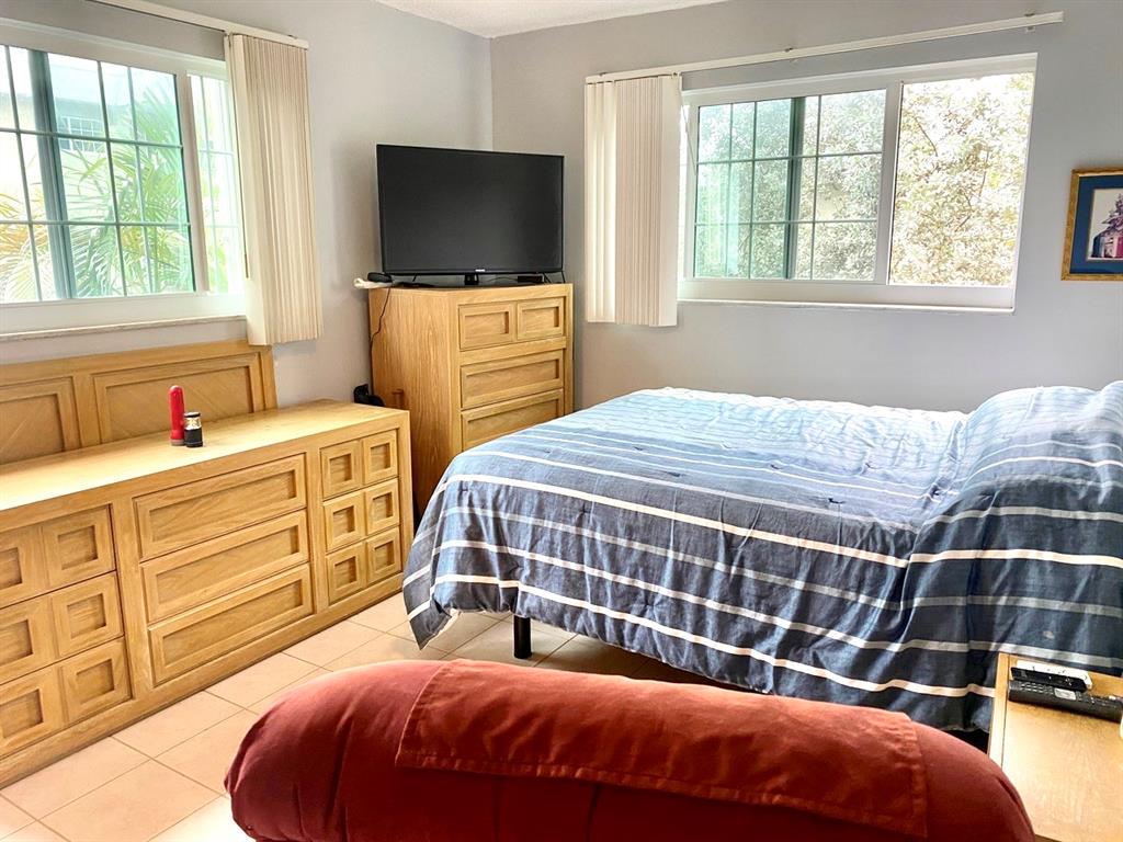 3002 Northeast 5th Terrace, Unit 209B Wilton Manors, FL 33334 - Photo 12 of 25 a bedroom with a bed and a flat tv screen on dresser